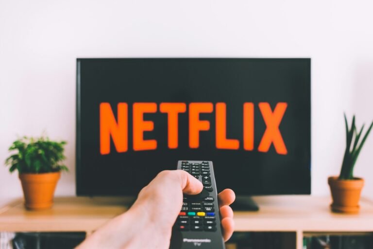 Hand, die eine Fernbedienung auf einen Fernseher richtet
