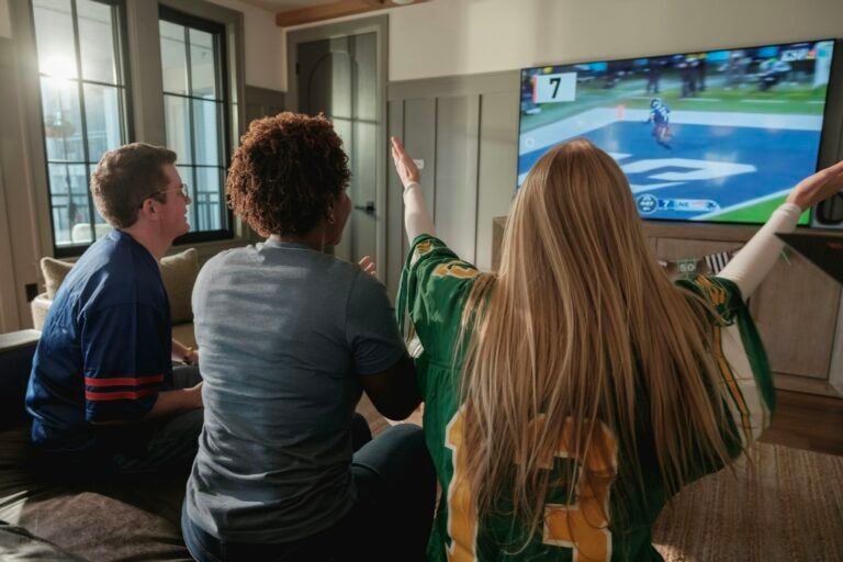 Freunde, die zu Hause gemeinsam ein Sportspiel im Fernsehen schauen